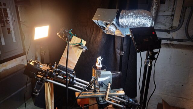 Photo of a setup for stop motion, with two LED lights, a webcam based stereo rig, a heat gun mounted on a slider, and a fan mounted over it.