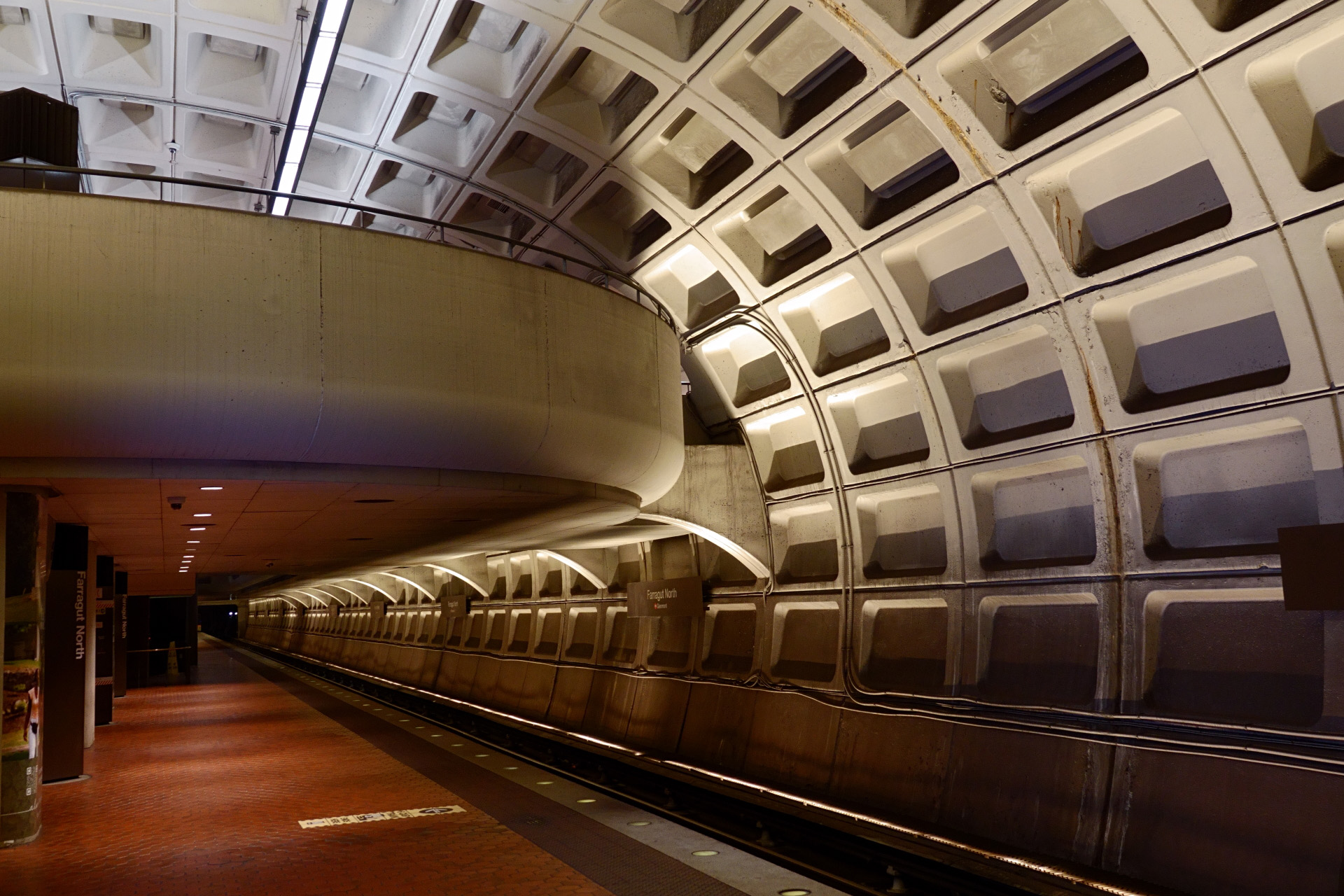 Interior of concrete metro station with arched roof and a mezzanine lever that somewhat looks like a balcony